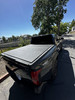 Shop Access LOMAX matte black tri-fold tonneau cover for 2024–2026 Toyota Tacoma 5ft bed. Low-profile hard folding cover. In stock and ready to ship.