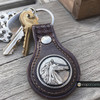 brown leather keychain with a silver-tone snap jewelry charm featuring a raised horse head profile and textured border