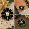 black enamel flower snap jewelry charm with gold trim and a white pearl center shown loose and installed on a silver bracelet