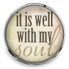 Round SnapAccents snap jewelry charm with inspirational quote "it is well with my soul" in black and beige text, silver metal frame, placed on wooden surface, ideal for interchangeable snap jewelry accessories.