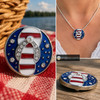 Round snap jewelry charm with a blue enamel background, red and white striped flip flop sandal, and clear rhinestones arranged around and on the sandal