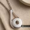 Silver SnapAccents snap jewelry pendant necklace with circular snap charm holder on textured beige fabric background, modern minimalist accessory for interchangeable snap buttons.