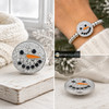 18mm snap jewelry charm featuring a snowman face covered in clear rhinestones with black eyes and mouth and an orange carrot nose, shown loose and on a silver beaded bracelet