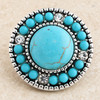 round snap jewelry charm with a large central turquoise stone surrounded by smaller turquoise beads and clear rhinestones in a silver-toned setting