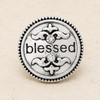silver-toned round snap jewelry charm with the word blessed, two clear rhinestones, and decorative scroll details