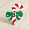 snap jewelry charm shaped like a red and white striped candy cane with a green bow and silver-tone trim on a light marble surface