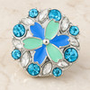 snap jewelry charm with teal and blue flower petals surrounded by blue and clear rhinestones in a silver setting