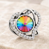snap jewelry charm with a multicolor faceted crystal center surrounded by a silver heart-shaped frame encrusted with clear rhinestones