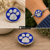 blue snap jewelry charm with a rhinestone-studded dog paw design on a bright blue enamel background shown loose and installed on a silver bracelet