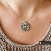 silver snap jewelry necklace with a round pendant featuring a detailed cross, filigree patterns, and the word Faith engraved
