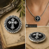 snap jewelry charm with a silver-tone detailed border and a rhinestone-studded Celtic cross on a black background, shown loose and worn on a silver necklace