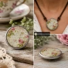 Round SnapAccents snap jewelry charm with vintage floral design and cursive script, featuring soft pink roses and green leaves in a silver-tone metal frame, ideal for interchangeable snap jewelry accessories.