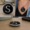 Black snap jewelry charm with a polished silver letter S on a glossy black enamel background shown loose and worn on a silver necklace chain