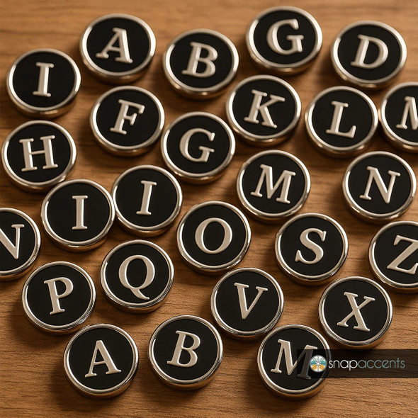 Black and silver SnapAccents snap jewelry charms featuring uppercase alphabet letters A to Z, arranged on a wooden surface, perfect for personalized snap bracelets, necklaces, and accessories.