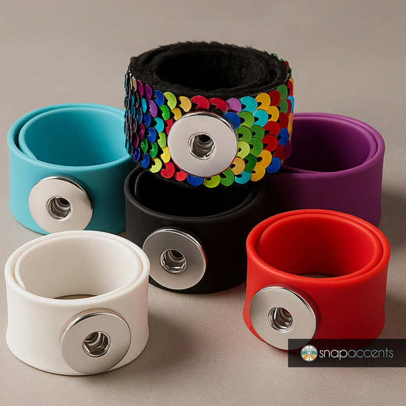 Colorful SnapAccents snap jewelry bands including blue, black, white, red, purple silicone bracelets and a multicolor sequin snap bracelet with silver snap button closures, displayed on a neutral background.
