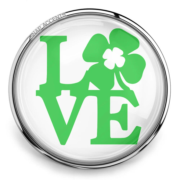 SnapAccents round snap jewelry charm with green "LOVE" text featuring a shamrock clover design, interchangeable decorative accessory for bracelets and necklaces, St. Patrick's Day themed fashion jewelry accent.