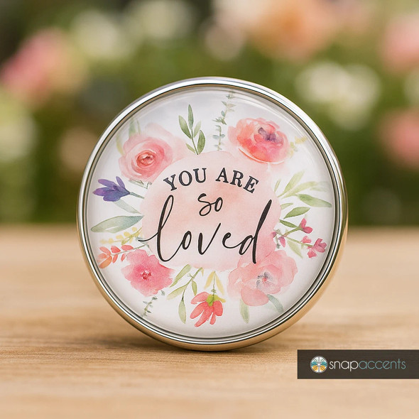 SnapAccents round snap jewelry charm with floral watercolor design and inspirational message "You Are So Loved" in elegant script, perfect for personalized snap bracelets, necklaces, or accessories, featuring soft pink, purple, and green tones on a white background, ideal gift for loved ones and positive affirmation jewelry.