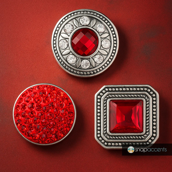 SnapAccents snap jewelry set featuring three interchangeable snap charms with vibrant red gemstones and intricate silver-tone metal designs, including a round faceted gem with clear accents, a cluster of small red crystals, and a square red gem with detailed beaded border, perfect for customizable fashion accessories and statement jewelry pieces.