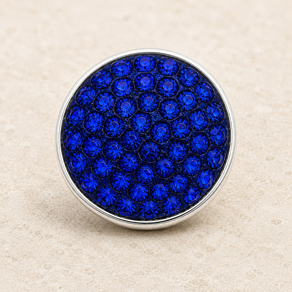 round snap jewelry charm covered with multiple royal blue rhinestones set in a silver-tone metal base