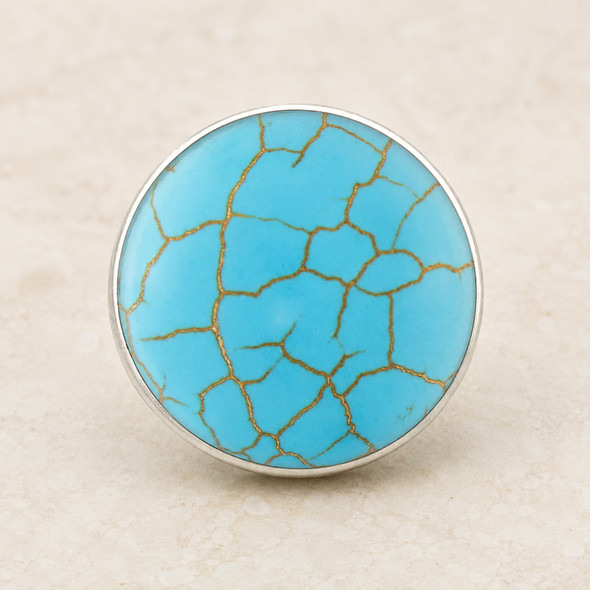 round snap jewelry charm with bright turquoise color and brown vein-like crack patterns in a silver-tone setting