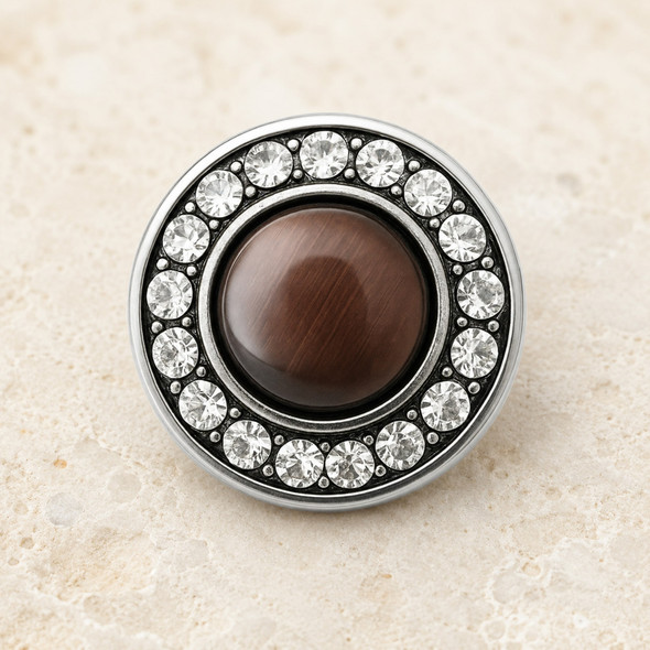 round snap jewelry charm with a glossy brown center pearl surrounded by a circle of clear rhinestones in a silver-tone setting