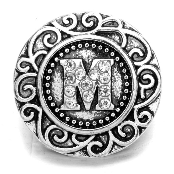 Silver SnapAccents snap charm with ornate scroll design and rhinestone-studded letter M centerpiece, decorative interchangeable jewelry accessory for bracelets and necklaces.
