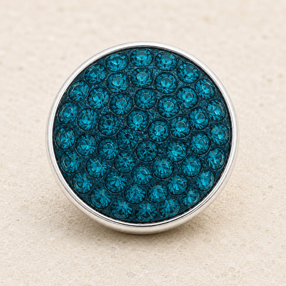 round snap jewelry charm covered with multiple teal rhinestones set in a silver-tone metal base