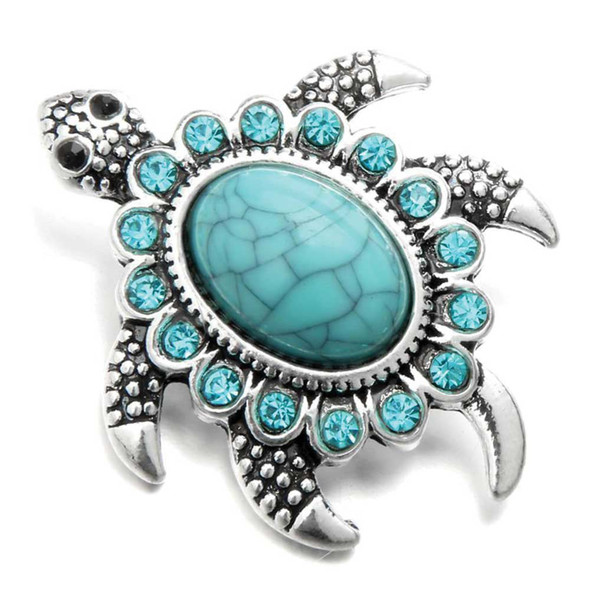 silver-toned snap jewelry charm shaped like a sea turtle with a large turquoise center stone and smaller turquoise rhinestones around the shell