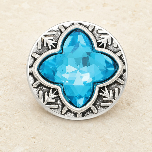 round snap jewelry charm with a faceted blue four-point rhinestone center and textured silver-tone background with leaf-like accents
