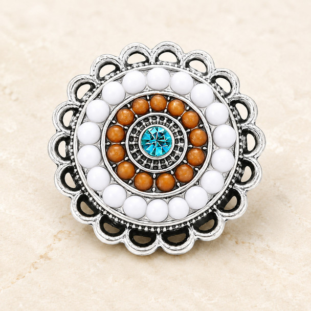 round snap jewelry charm with concentric circles of white and brown beads and a central aqua rhinestone set in a silver scalloped edge base