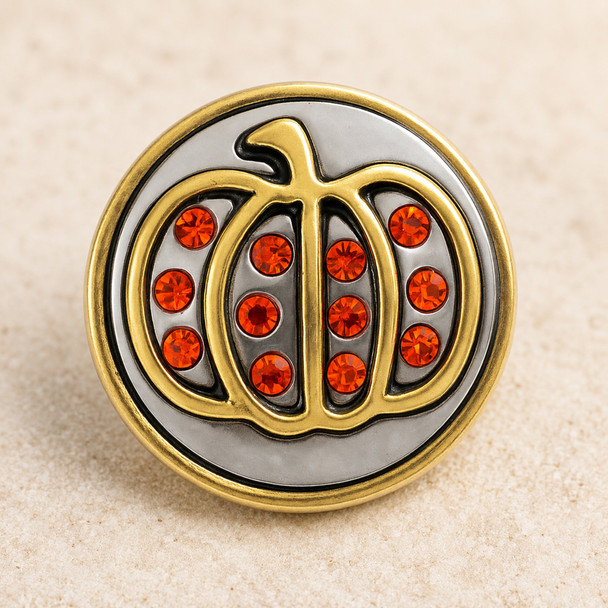 round snap jewelry charm with a brass pumpkin outline and bright orange rhinestones on a silver background