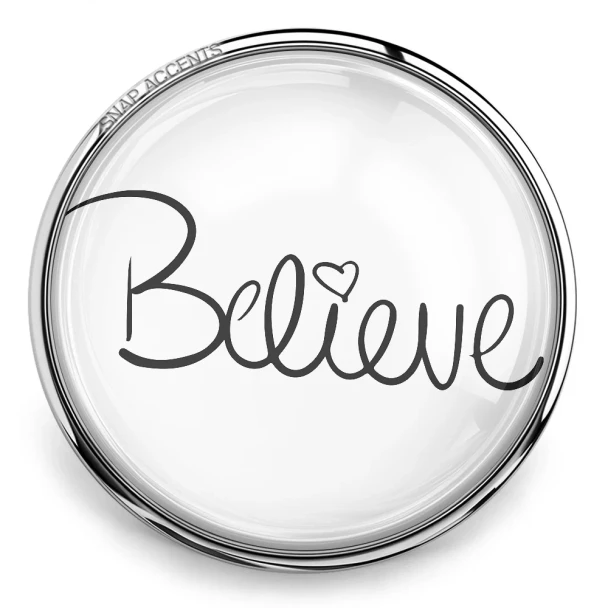 SnapAccents round snap jewelry charm with the word "Believe" in elegant black script and a heart detail, silver metal frame, inspirational accessory for interchangeable snap jewelry, perfect for bracelets, necklaces, and gifts.