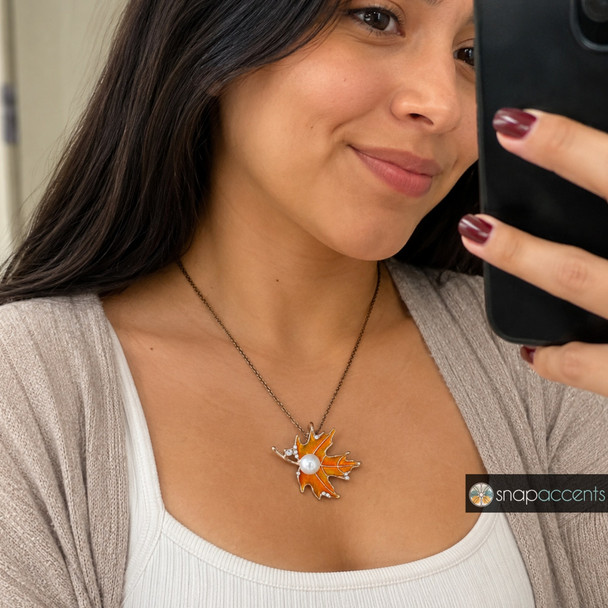 snap jewelry necklace with an orange enamel autumn leaf pendant accented by a white pearl and small rhinestones on a dark chain
