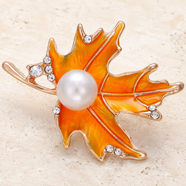 snap jewelry charm shaped like an orange enamel autumn leaf with a central white pearl and small clear rhinestones on the edges