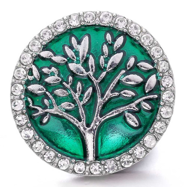 Round SnapAccents snap jewelry charm with silver tree design on emerald green background, surrounded by clear rhinestone border, decorative interchangeable accessory for bracelets and necklaces.