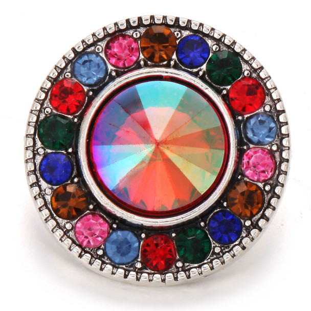 round snap jewelry charm with a large iridescent faceted center stone surrounded by alternating pink, blue, green, red, and brown rhinestones set in a silver-tone base