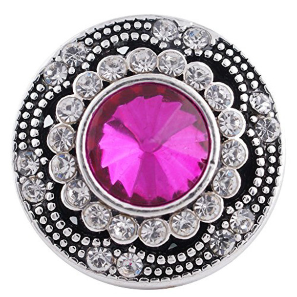 round snap jewelry charm with a large faceted pink center stone surrounded by two rows of clear rhinestones on a silver-tone base