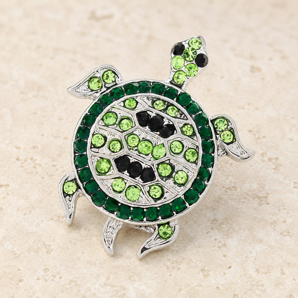 snap jewelry charm shaped like a sea turtle with green and black rhinestones on a silver base
