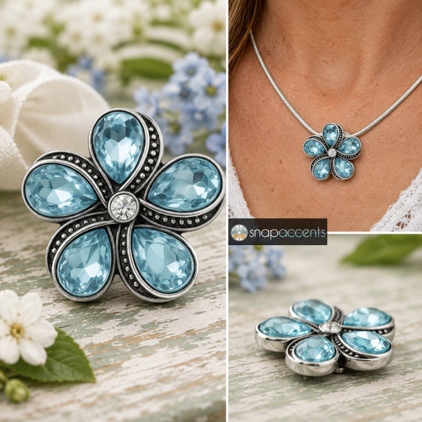 snap jewelry charm shaped like a flower with five light blue teardrop rhinestones and a clear center stone set in vintage gray metal with beaded detailing