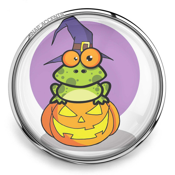 SnapAccents Halloween snap jewelry featuring a cute green frog wearing a purple witch hat sitting on a carved jack-o'-lantern pumpkin with a purple background, perfect for festive seasonal accessories.