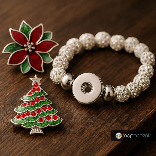 Silver snap jewelry bracelet with sparkling rhinestone beads, featuring interchangeable Christmas-themed snap charms including a red and green poinsettia flower and a decorated Christmas tree, displayed on a wooden surface, SnapAccents brand.