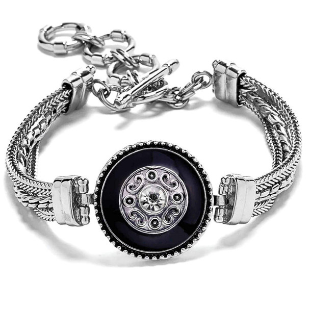 silver metal snap jewelry bracelet with a black enamel circular snap featuring a central clear rhinestone and decorative silver scrollwork, secured with a toggle clasp