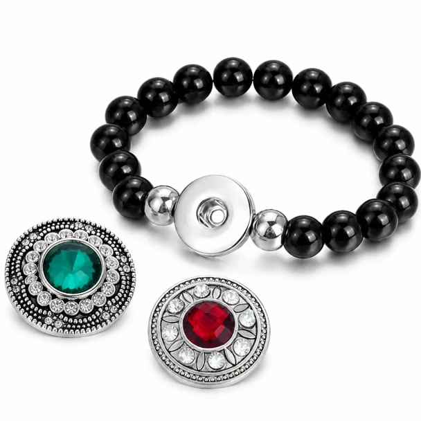 Black beaded snap bracelet with interchangeable decorative snap charms featuring green and red gem centers surrounded by clear rhinestones, stylish snap jewelry accessory for women.