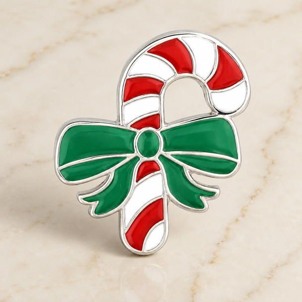 snap jewelry charm shaped like a red and white striped candy cane with a green bow and silver-tone trim on a light marble surface