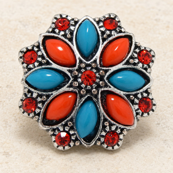 snap jewelry charm with a flower design featuring alternating dark coral and teal petal shapes surrounded by red rhinestones in a silver-tone setting
