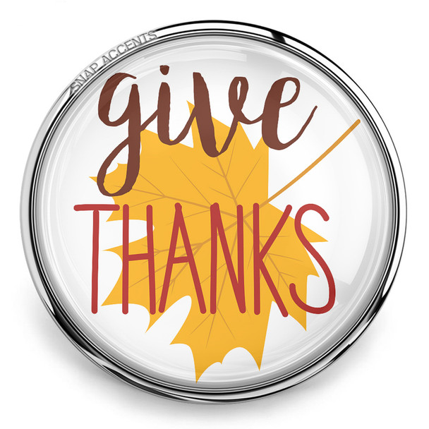 round snap jewelry charm with a yellow maple leaf and the words give THANKS in brown and red script inside a silver metal frame