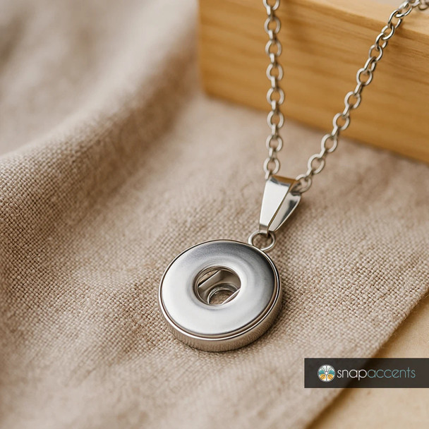 Silver snap charm pendant necklace with circular donut design on delicate chain, customizable snap jewelry accessory by SnapAccents, modern minimalist fashion piece for women, perfect gift idea, displayed on beige fabric background.