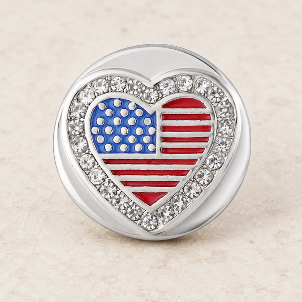 Round snap jewelry charm with a heart-shaped American flag design in red, white, and blue, surrounded by clear rhinestones on a silver base