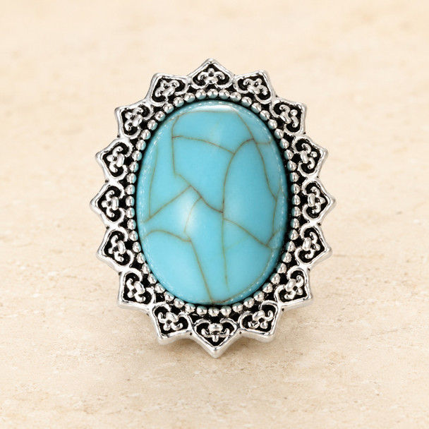 snap jewelry charm with an oval turquoise center stone surrounded by an ornate silver-toned border with intricate detailing