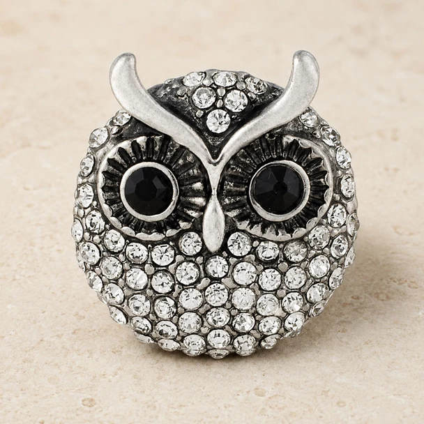 owl-shaped snap jewelry charm covered in clear rhinestones with black rhinestone eyes and silver metal accents